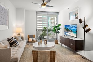 A living room with a couch, a chair, a table, a television, and a ceiling fan.